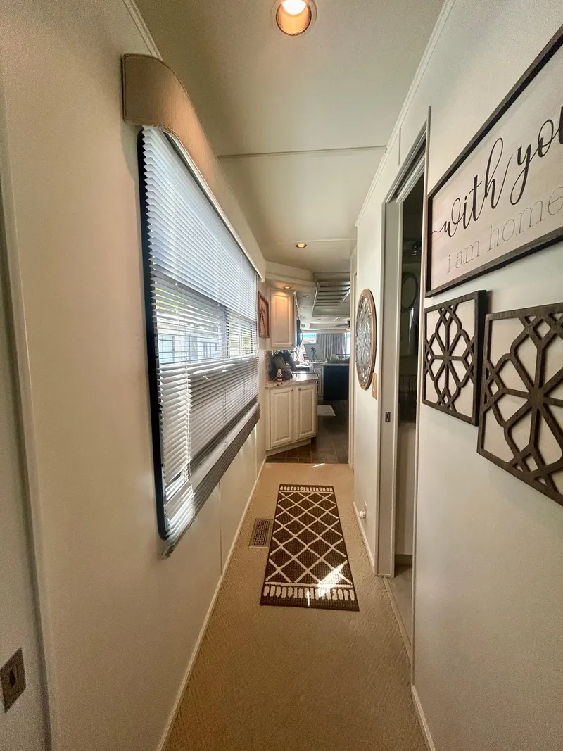 Slide: The Image of Narrow hallway inside a 2002 Sumerset houseboat with decorative wall art and carpet. - 24