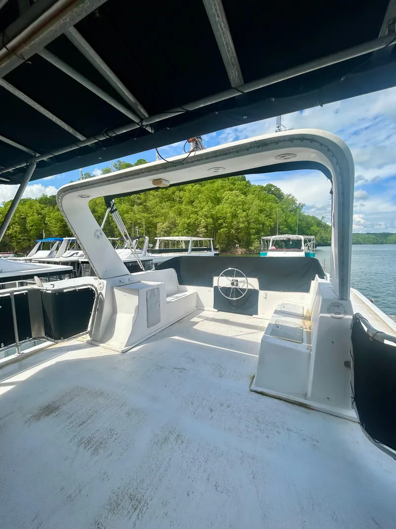 Slide: The Image of 2002 Sumerset houseboat deck with seating, steering wheel, and scenic lake view. - 30