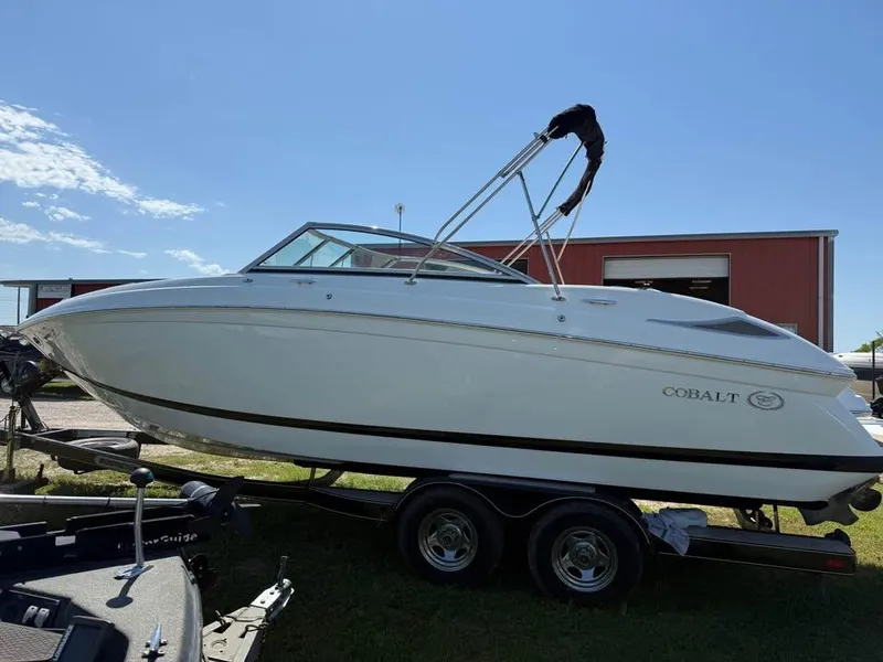 Slide: The Image of 2012 Cobalt 242 boat on trailer, parked outdoors under clear blue sky. - 1