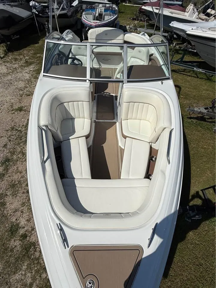 Slide: The Image of 2012 Cobalt 242 boat with white seating and open bow design, parked on grass. - 4