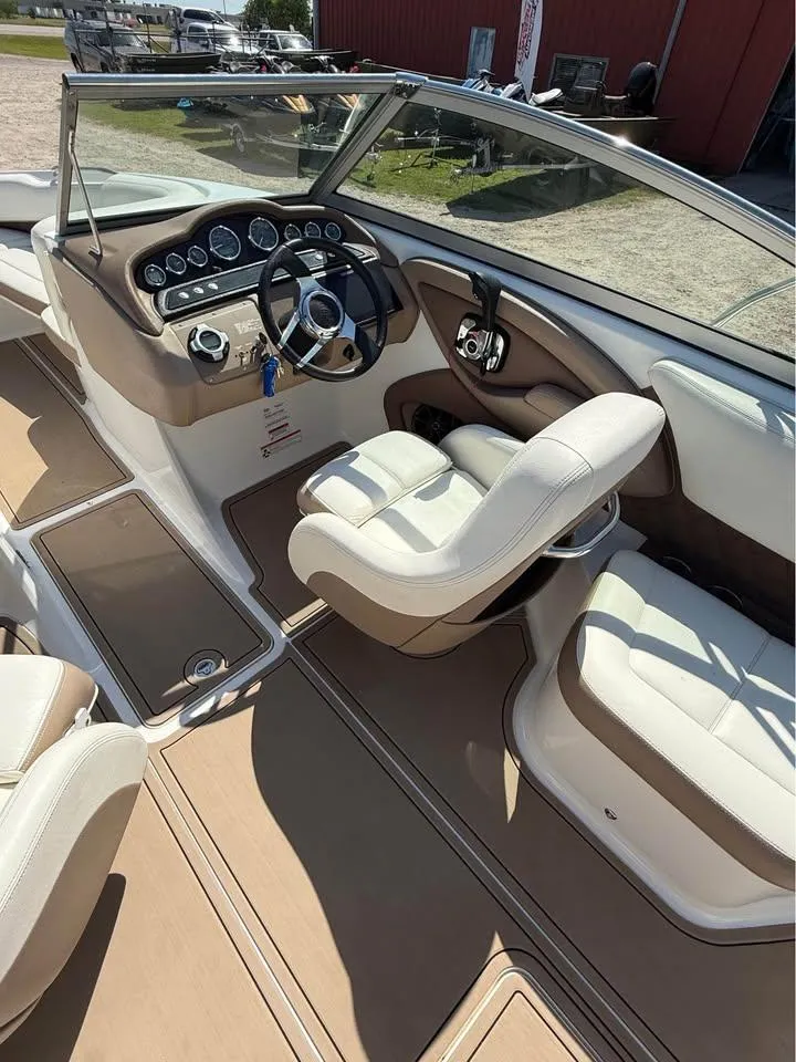 Slide: The Image of 2012 Cobalt 242 boat interior with beige seating and modern dashboard. - 8