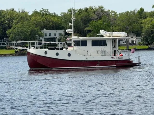 Slide: The Image of 2005 Great Harbour N37 boat named Magnolia on a calm river with lush greenery. - 0