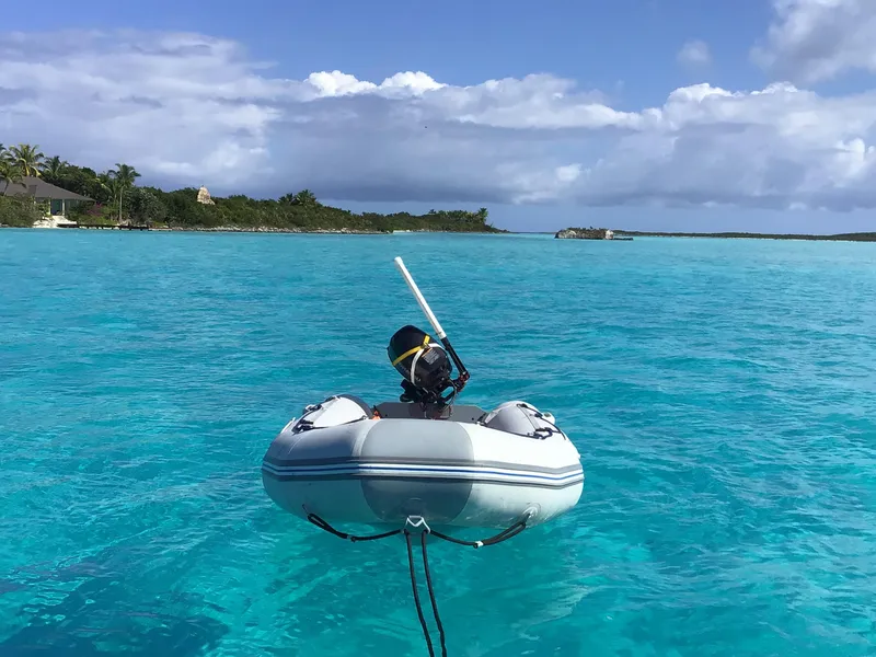 Slide: The Image of Inflatable dinghy floating on turquoise water near lush island, clear skies above. - 27