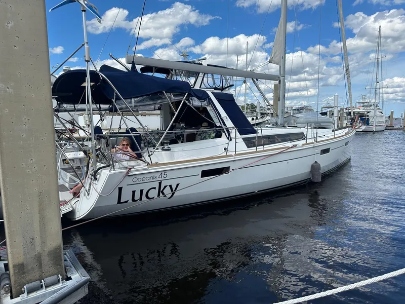The Image of 2014 Beneteau Oceanis 45 sailboat named "Lucky" docked at a marina under a blue sky. - 0