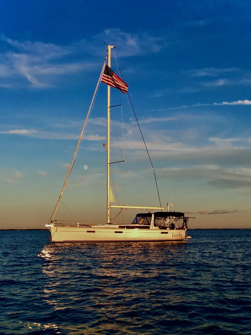 Slide: The Image of 2014 Beneteau Oceanis 45 sailboat on calm water at sunset with American flag. - 47