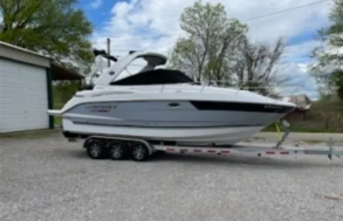 Slide: The Image of 2022 Monterey 295 Sport Yacht on trailer, parked outdoors with trees and cloudy sky. - 1