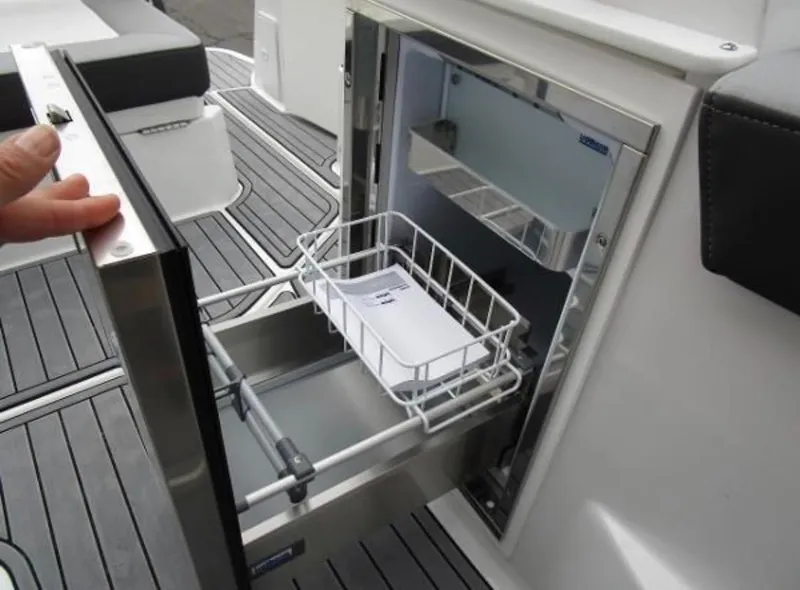 Slide: The Image of 2022 Monterey 295 Sport Yacht refrigerator with open stainless steel door and wire basket. - 10