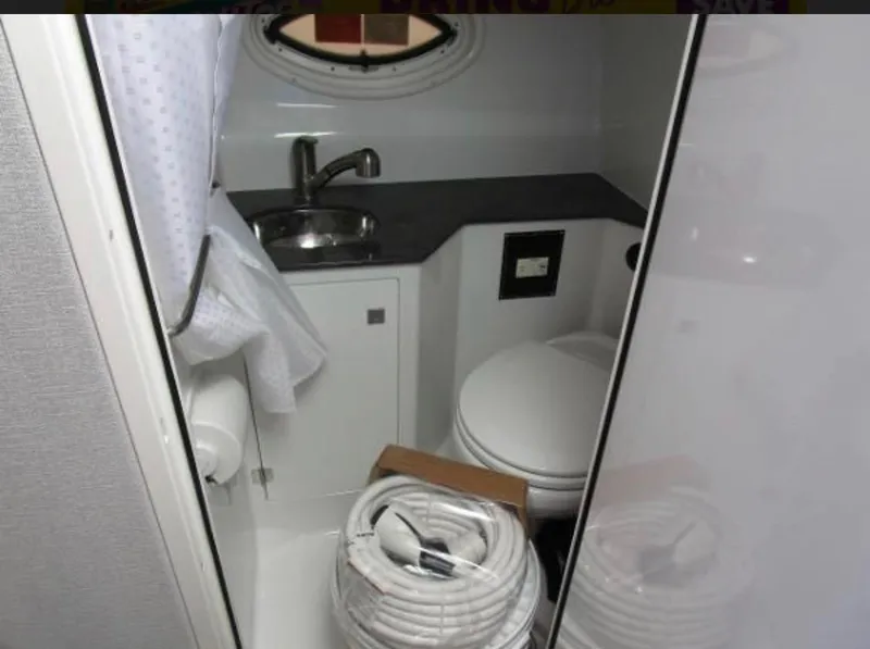 Slide: The Image of 2022 Monterey 295 Sport Yacht bathroom with sink, toilet, and coiled hose. - 12
