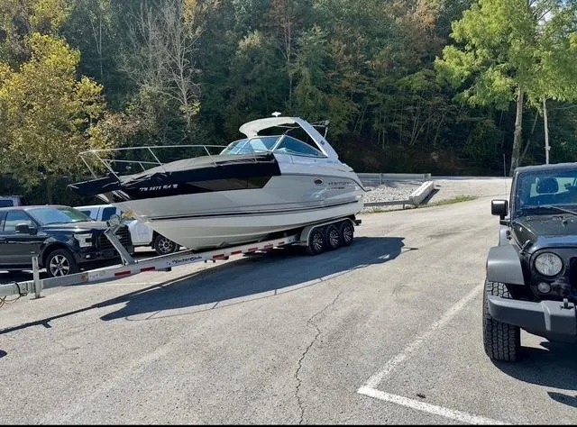 Slide: The Image of 2022 Monterey 295 Sport Yacht on trailer in parking lot, surrounded by trees and vehicles. - 2