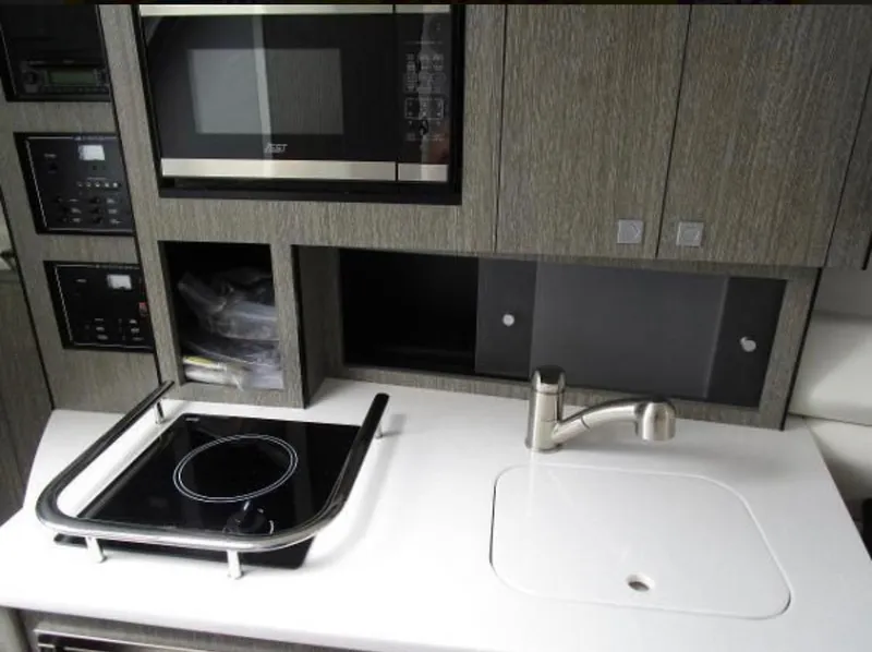 Slide: The Image of 2022 Monterey 295 Sport Yacht kitchen with stove, sink, and microwave. - 9