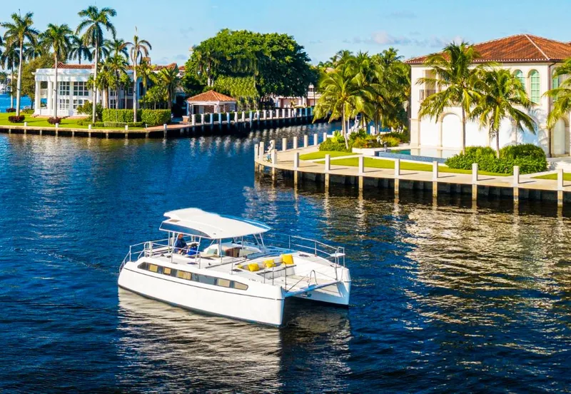 Slide: The Image of 2025 Smart Cat M280 Power yacht cruising near luxurious waterfront homes and palm trees. - 1