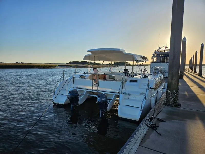 Slide: The Image of 2025 Smart Cat M280 Power catamaran docked at sunset, featuring dual outboard motors. - 7