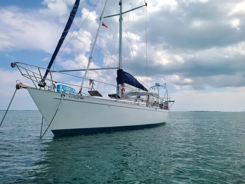 Slide: The Image of Sailboat Kelly Peterson 44, 1981 model, anchored on calm sea under cloudy sky. - 11