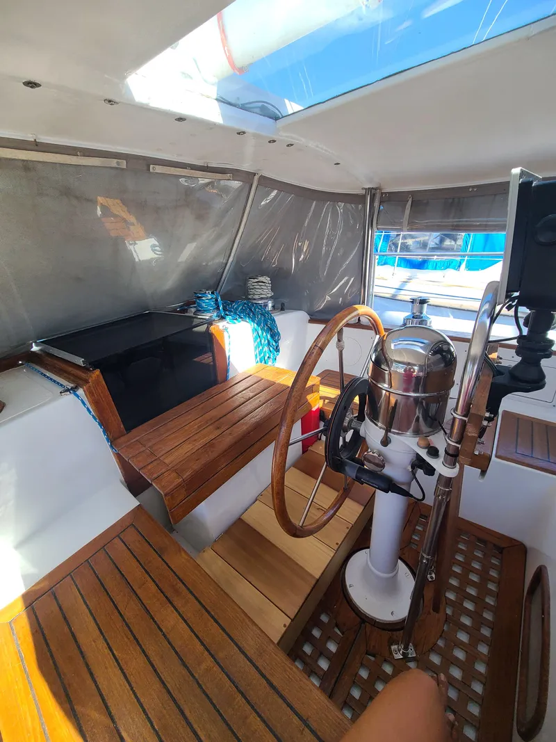 Slide: The Image of Cockpit of 1981 Kelly Peterson 44 sailboat with wooden seating and steering wheel. - 28