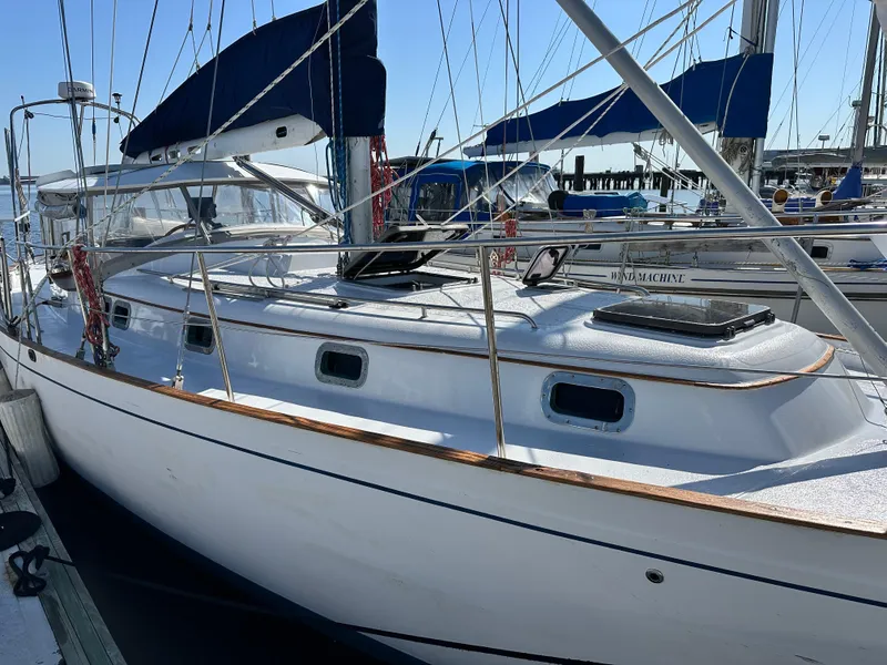 Slide: The Image of 1981 Kelly Peterson 44 sailboat docked, featuring sleek design and blue sail covers. - 3