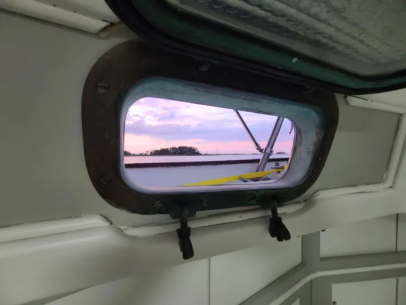 Slide: The Image of Porthole view from 1981 Kelly Peterson 44 sailboat, showcasing serene sunset over water. - 42