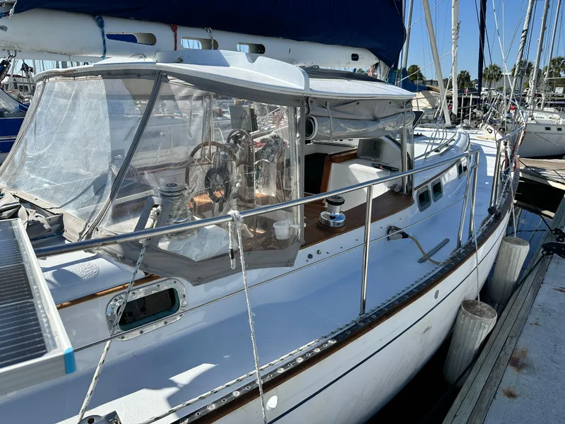 Slide: The Image of 1981 Kelly Peterson 44 sailboat docked, featuring a clear cockpit enclosure and wooden accents. - 5