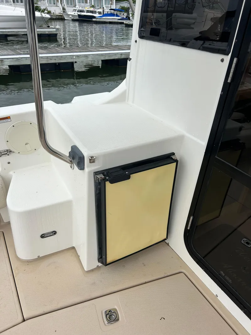 Slide: The Image of 2014 Cutwater C-30 Sedan boat interior with compact fridge and dock view. - 6