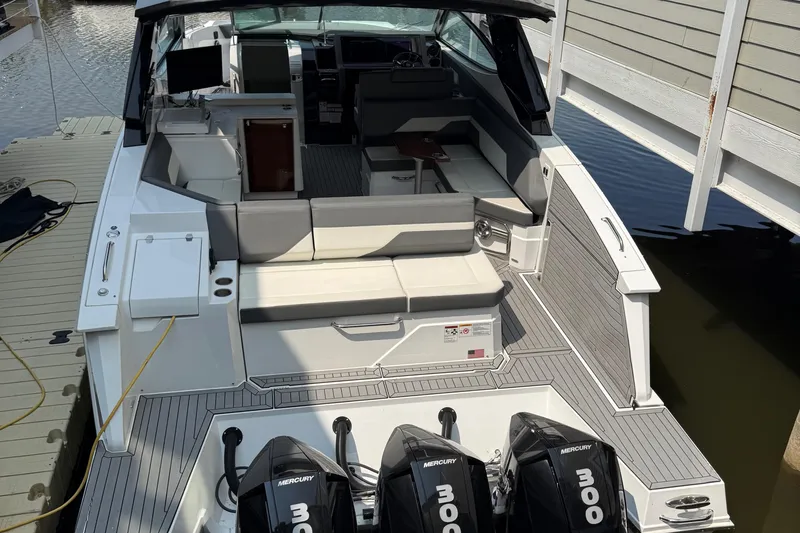 Slide: The Image of 2021 Cruisers Yachts 38 GLS OB with triple Mercury outboards, docked, showcasing spacious seating. - 38