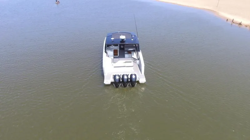 Slide: The Image of 2021 Cruisers Yachts 38 GLS OB on calm water, rear view with triple outboard engines. - 49