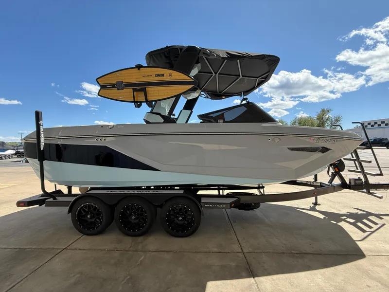 Slide: The Image of 2023 Nautique Super Air G23 boat on trailer with surfboards, under clear blue sky. - 5