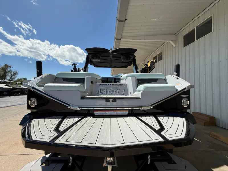 Slide: The Image of 2023 Nautique Super Air G23 boat, rear view, docked under a sunny sky. - 8