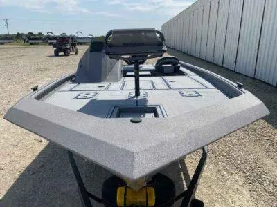 Slide: The Image of 2025 SeaArk Flex 19 Pro boat, gray deck, parked outdoors near storage facility. - 2
