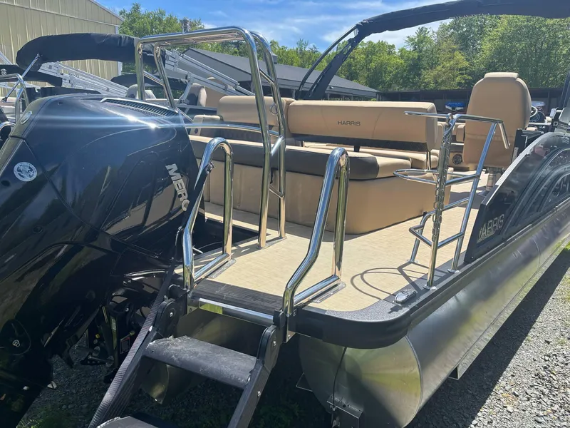 Slide: The Image of 2025 Harris Sunliner 230 SL pontoon boat with Mercury engine, beige seating, and stainless steel railings. - 7
