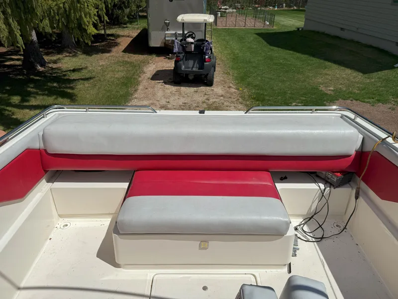 Slide: The Image of 1988 Slickcraft 268 SC boat interior with red and gray seating, parked near a golf cart. - 16