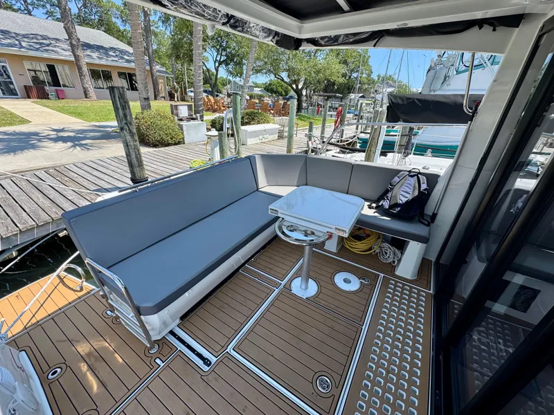 Slide: The Image of 2024 Beneteau Antares 11 boat deck with seating and table, docked at marina. - 12