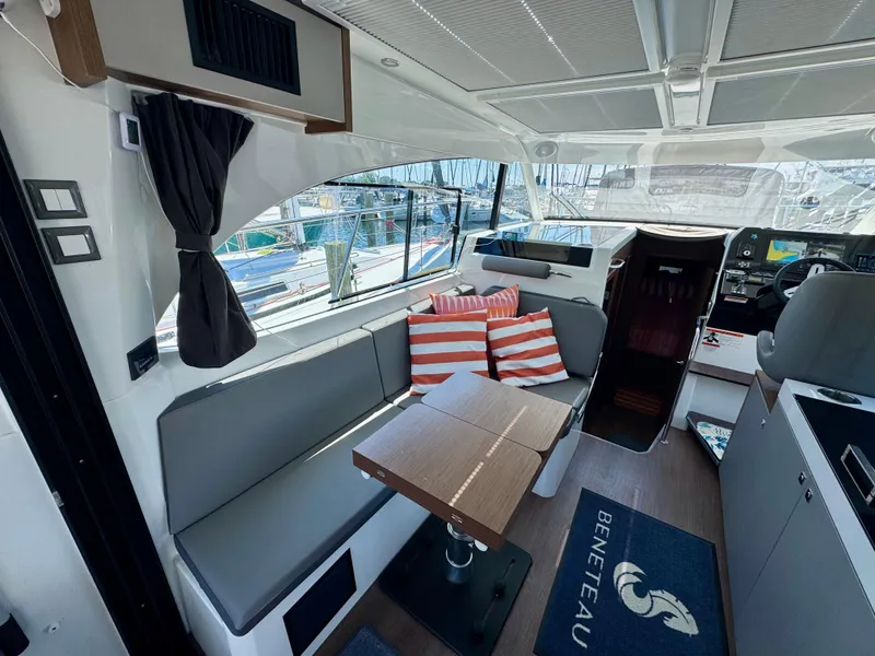 Slide: The Image of 2024 Beneteau Antares 11 interior with seating, table, and striped cushions. - 15