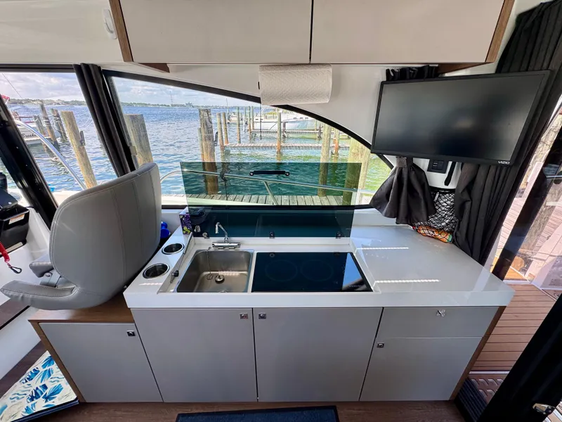 Slide: The Image of 2024 Beneteau Antares 11 interior kitchen with sink, stove, and waterfront view. - 19