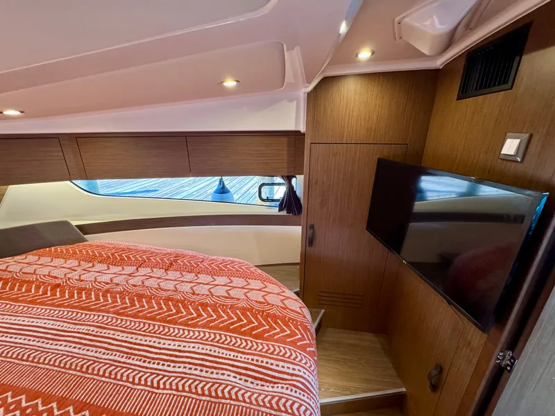 Slide: The Image of 2024 Beneteau Antares 11 cabin interior with bed, TV, and wood paneling. - 24