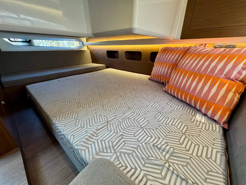 Slide: The Image of 2024 Beneteau Antares 11 cabin with geometric bedding and colorful pillows. - 27