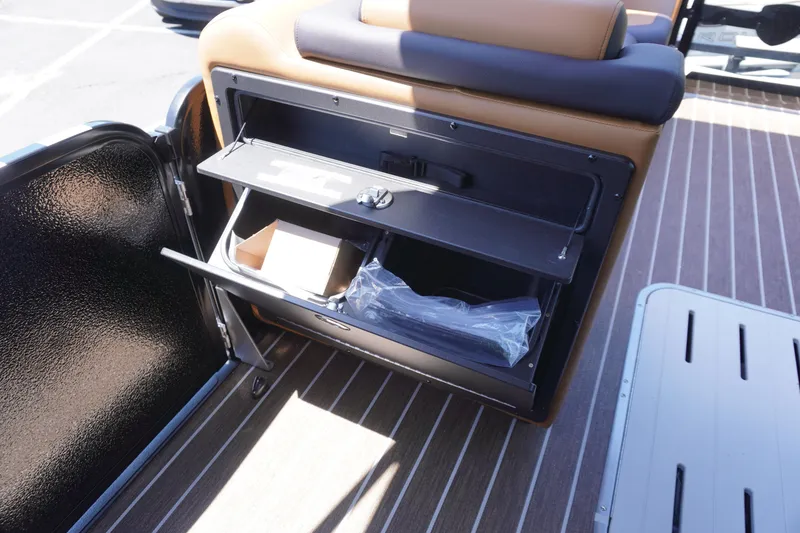 Slide: The Image of 2025 Premier 250 Sunsation RS boat storage compartment with open shelves and brown seating. - 13
