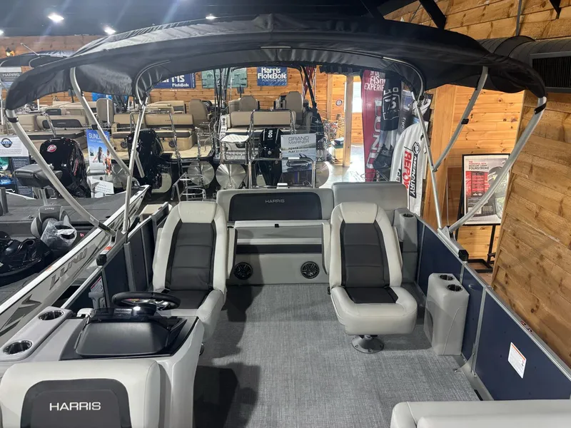 Slide: The Image of 2025 Harris Cruiser 210 pontoon boat with spacious seating and canopy in showroom. - 12