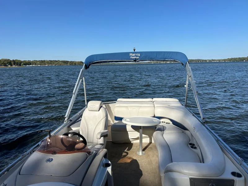 Slide: The Image of 2006 Harris 230 Royal Heritage pontoon boat on a serene lake under clear blue skies. - 3