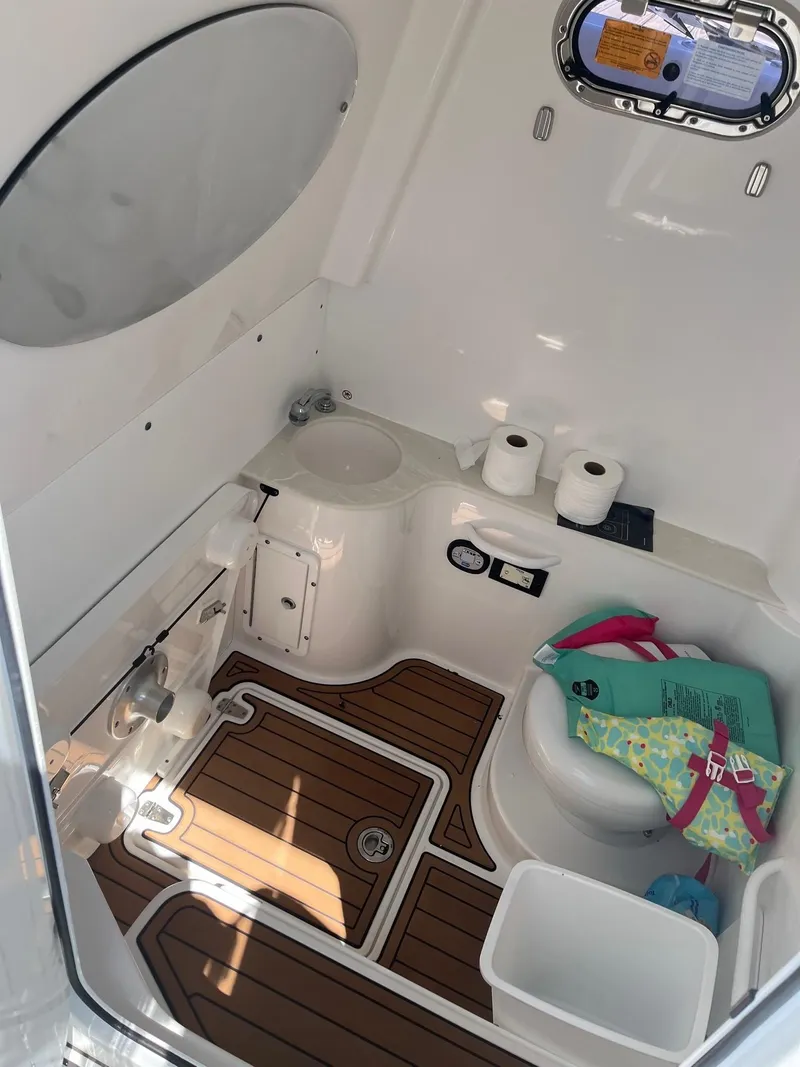 Slide: The Image of 2021 Edgewater 340CC boat interior with wooden flooring and compact bathroom amenities. - 11