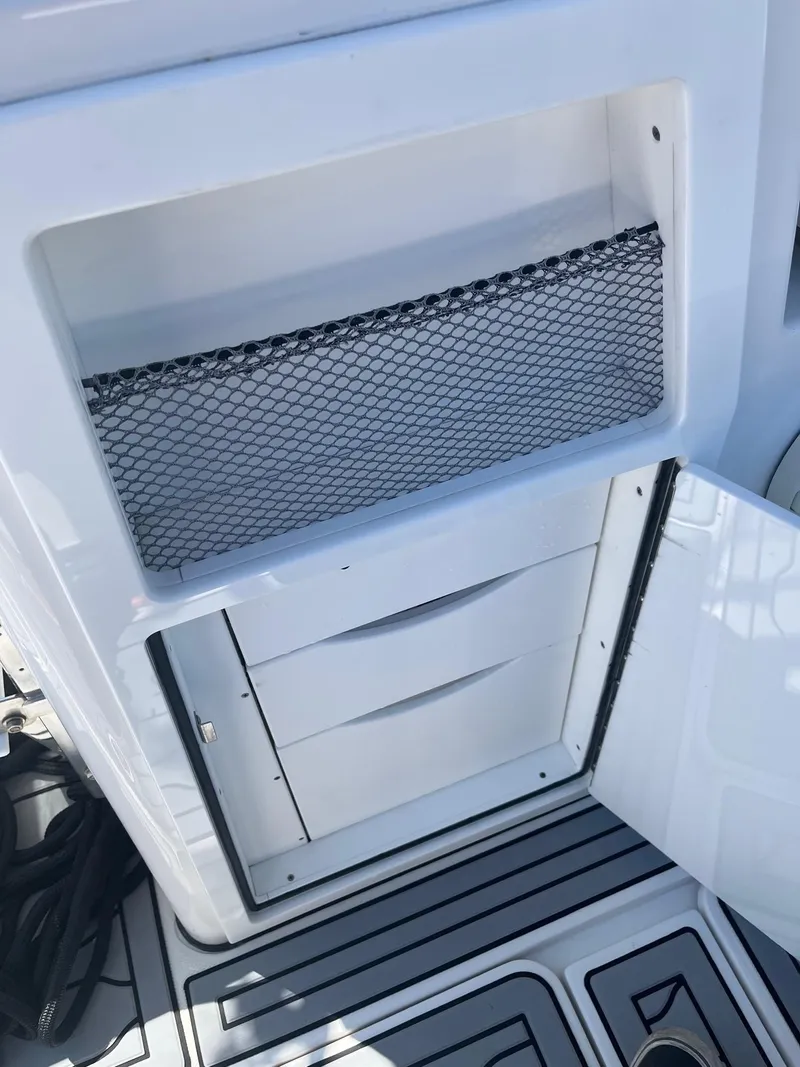 Slide: The Image of 2021 Edgewater 340CC boat storage compartment with open door and drawers. - 14