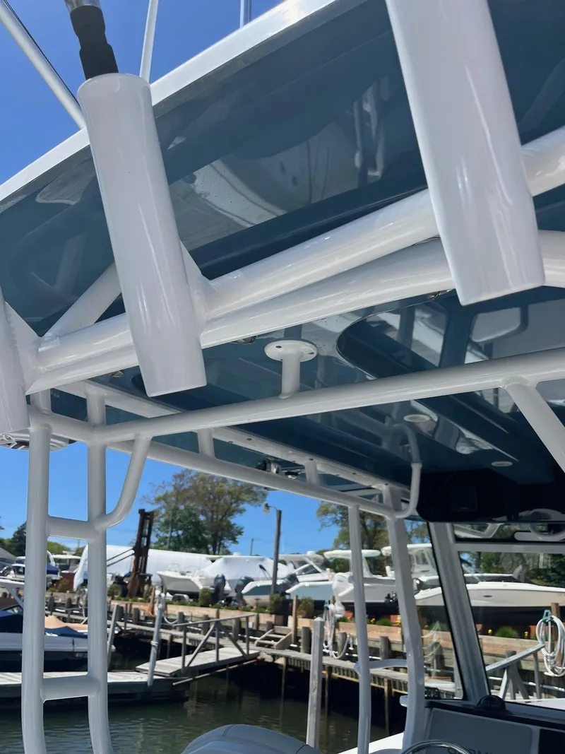 Slide: The Image of 2021 Edgewater 340CC boat with sleek white framework and blue canopy at a marina. - 17