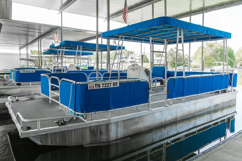 Slide: The Image of Custom 2000 pontoon rental fleet with blue canopies docked in a covered marina. - 12