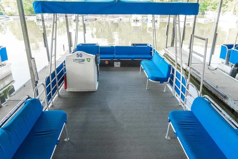 Slide: The Image of Spacious 2000 Custom Pontoon Rental Fleet with blue seating and canopy on a calm lake. - 16