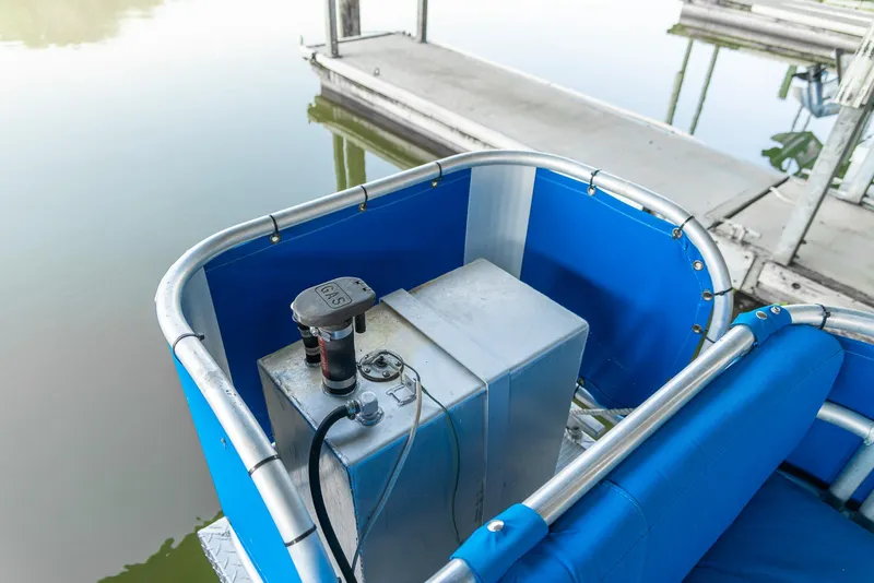 Slide: The Image of Pontoon boat corner with blue seating and control panel, docked on calm water. - 30