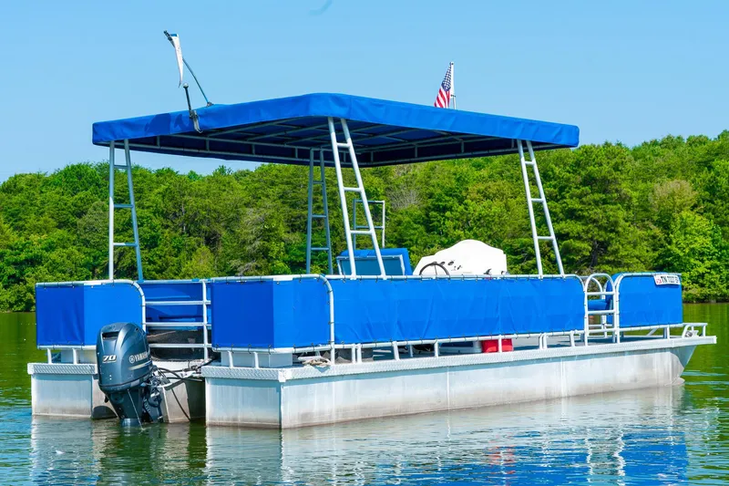 Slide: The Image of Custom 2000 pontoon boat with blue canopy on a calm lake, surrounded by trees. - 9