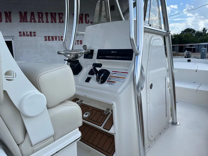 Slide: The Image of 2025 Pathfinder 2400 Open boat console with steering wheel and controls, in a marine service area. - 12