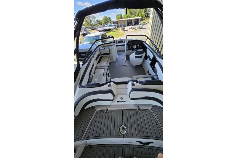 Slide: The Image of 2025 Yamaha Boats AR195 interior with seating and steering wheel, docked outdoors. - 13