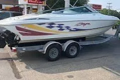 Slide: The Image of 2000 Baja 232 Islander boat on trailer, featuring colorful graphics, parked outdoors. - 1