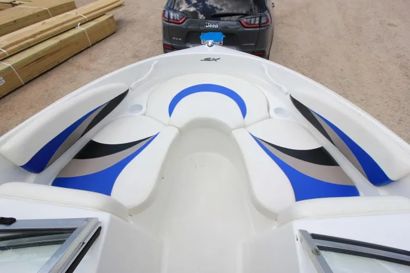 Slide: The Image of 2003 Glastron SX 175 boat interior with blue and black seating, parked near a Jeep. - 18