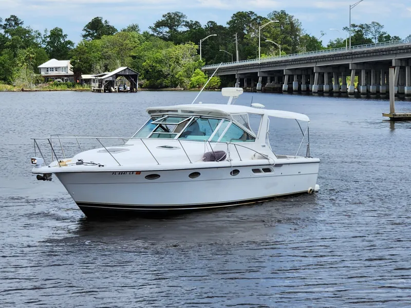 The Image of 2001 Tiara Yachts 3100 Open boat on a river near a bridge and trees. - 0