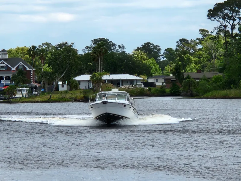 Slide: The Image of 2001 Tiara Yachts 3100 Open cruising on a scenic river with lush greenery. - 4